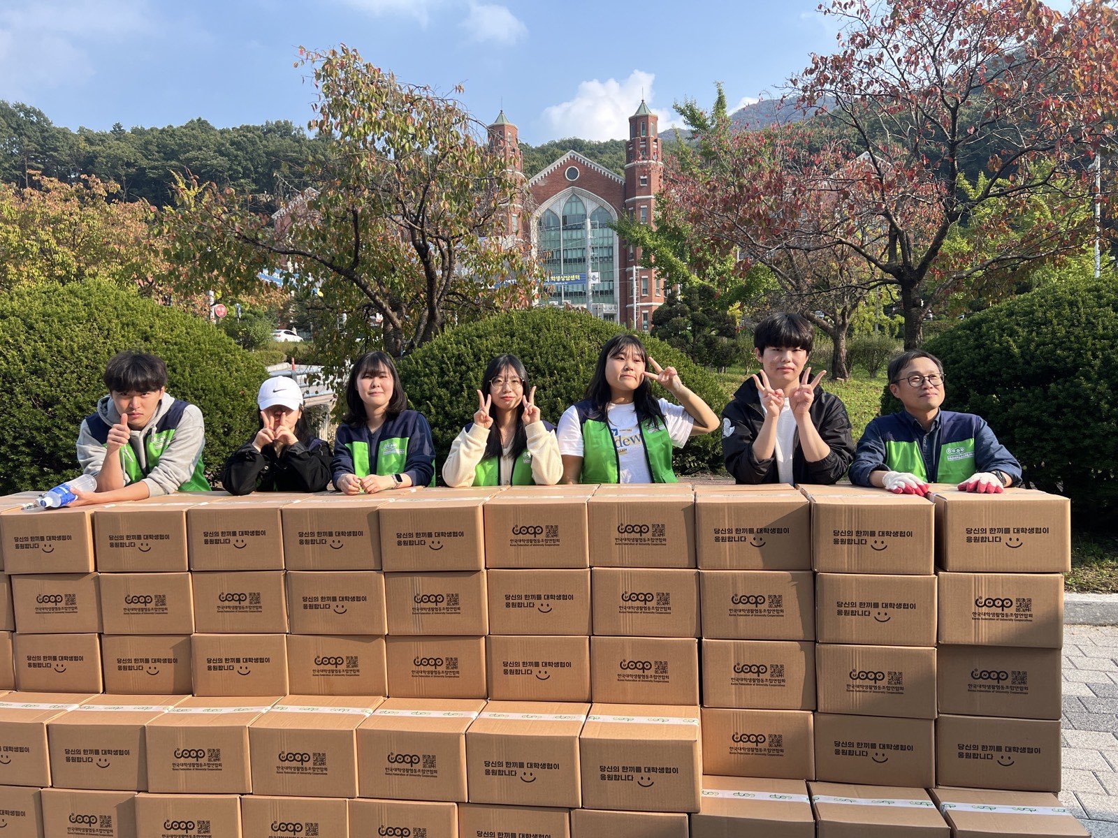 포장을 마친 꾸러미가 벽처럼 쌓여 있고, 그 뒤에 학생 자원봉사자와 대학생협 활동가들이 서 있는 모습